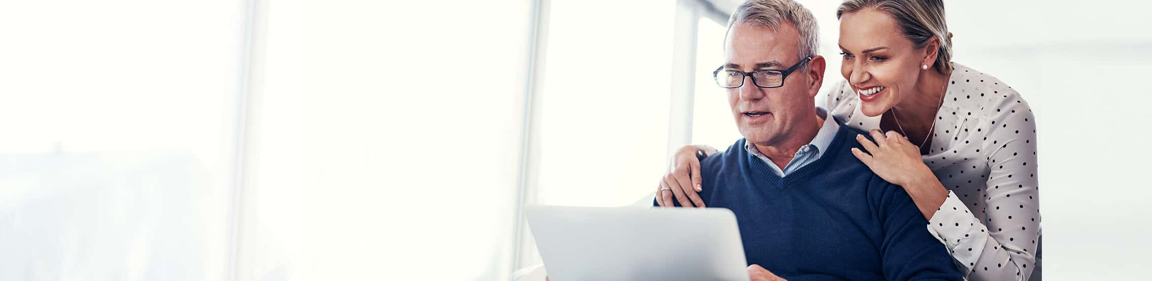 couple hugging and smiling while in from of laptop computer on kitchen counter