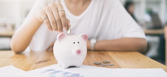 hand putting coins in a white piggy bank