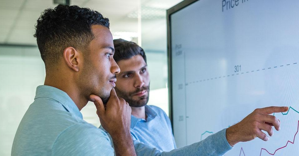 Two people looking over a white board, deep in thought