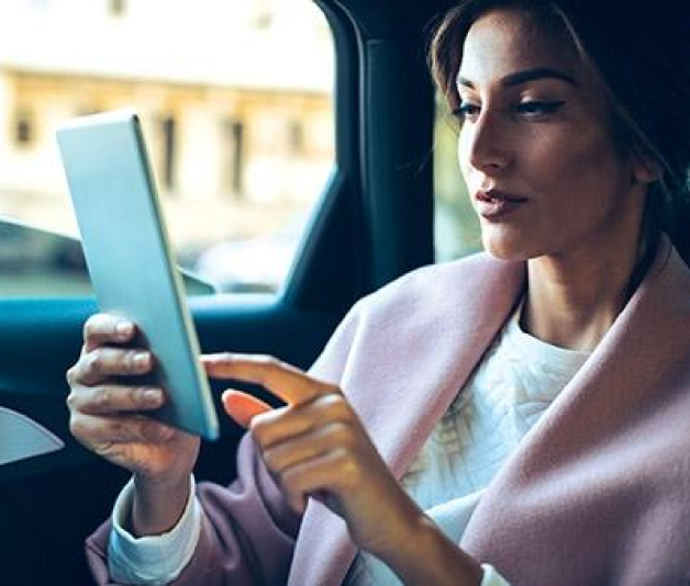 Woman on an iPad in a car, typing on the screen