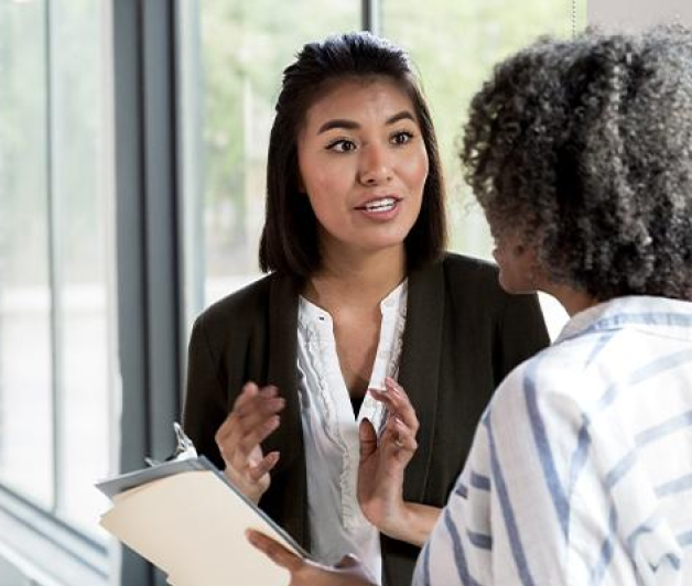 Two businesswomen discussing something with a clipboard