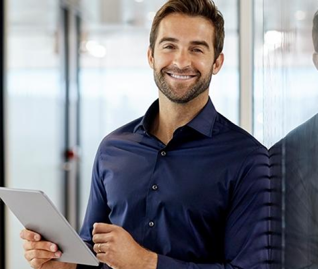 Man in collared shirt smiling with pen and papers in hand