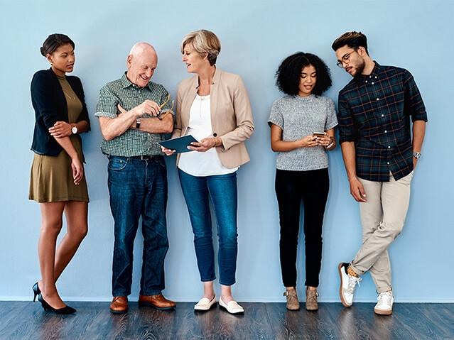 Group of five co-workers standing side by side and conversing