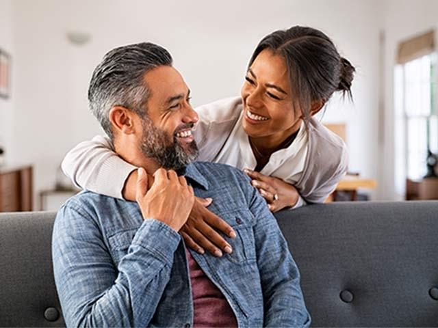 Husband and wife together in living room of home, embracing