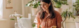 A woman sits at desk in home smiling